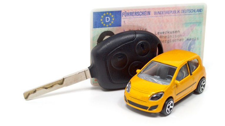 Führerschein, Autoschlüssel und gelbes Modellauto