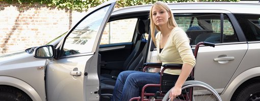 Frau in Rollstuhl vor geöffneter Autotür