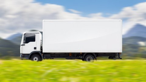 Weißer Lkw fährt über ländliche Straße bei schönem Wetter