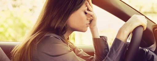 Ein Fehler in der praktischen Prüfung ist leider schnell passiert. Frau sitzt verzweifelt am Steuer