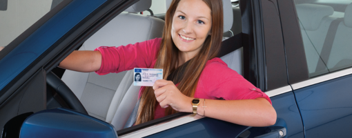Junge Autofahrerin zeigt stolz ihren Führerschein.