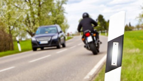 Motorrad und Auto auf Straße mit Leitpfosten