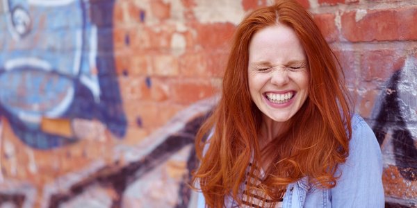 Redhead laughs in front of graffiti wall