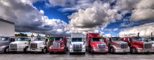 Große Trucks stehen nebeneinander vor wolkigem Himmel