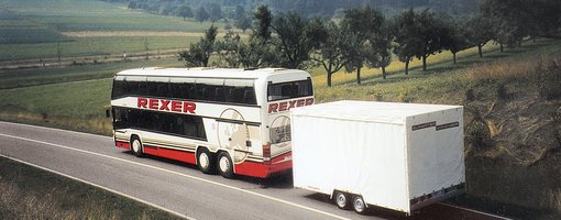 Reisebus mit Anhänger fährt über Landstraße