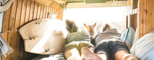 Pärchen liegt mit Surfboard in Camper