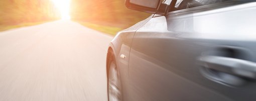 Auto fährt schnell über Straße in die Sonne