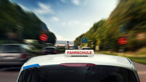 Schnelles Fahrschulauto fährt weg in Richtung vieler Schilder