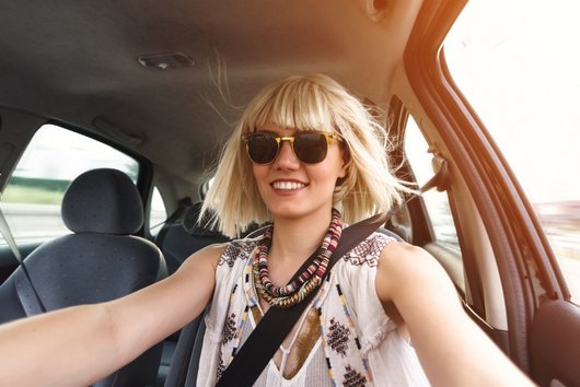 Blonde Frau mit Sonnenbrille sitzt im Auto