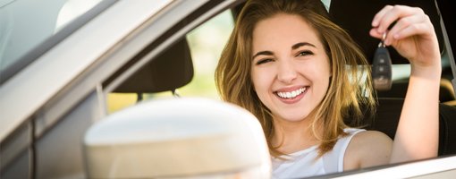 Glückliches Mädchen hält im Auto Autoschlüssel