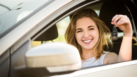 Glückliches Mädchen hält im Auto Autoschlüssel